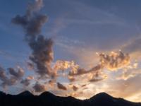 Angestrahlte Wolkenhaufen am Abendhimmel über den Bergen